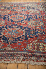 Angled detail of antique Soumac carpet, navy, cherry red geometric pinwheel patterns and low pile.