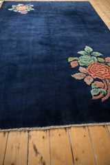 Deep cobalt blue field of a vintage Nichols Art Deco carpet with blush, tangerine, jade floral corner design.