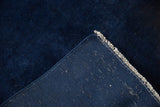 Close-up shows the dark blue plain weave foundation and off-white fringe of the vintage rug.