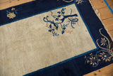 Detailed view of vintage Peking rug's antique ivory field, cobalt blue border, and delicate branch motif.