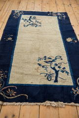 Cobalt blue tree, bird, and fringe on vintage Peking rug's antique ivory field.