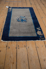 Angled view of a Vintage Peking rug showing central pictorial vase, planters in cobalt, silver, beige.