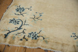 Peking rug corner: deep navy floral branches on cream field, displaying original selvage.