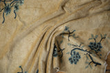 Folded detail of the circa 1910's Peking rug, showing blue floral branches on pale dusty gold pile.