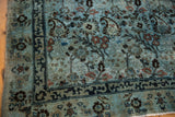 Distressed Meshed carpet corner, dusty blue, dark indigo border, blush florals, visible wear.
