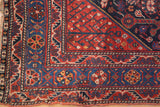 Vintage Shiraz rug corner, with geometric saffron red, indigo blue, and ivory borders.