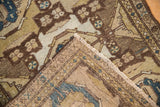 Distressed Hamadan rug corner, showing worn pile, visible foundation, and side cord selvage.
