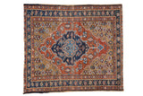 Vintage Persian Heriz rug with a geometric navy medallion, rust-red field, and deep gold spandrels.