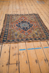 Angled view of a vintage Heriz square rug showing the navy blue medallion and rich gold ground.