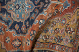 The textured, low pile of a vintage Heriz rug showing even wear in brick red, gold, and navy blue.