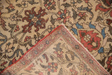 Antique Fereghan rug's folded corner showcases hand-knotted ivory field, vinery, and red selvage.