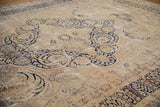 Distressed vintage Kerman carpet showing deep navy vinery and floral forms on an ivory field.