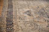 Distressed vintage Kerman carpet's dark navy millefleur border and faded gold field with exposed foundation.