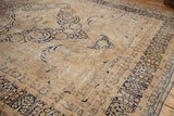 Distressed millefleur border of the vintage Kerman carpet, showing muted ivory and navy blue.