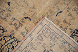 Distressed Kerman carpet's folded corner reveals worn pile, foundation, and intricate back pattern.