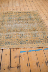 Distressed edge of the vintage gold and dusty blue rug, showing low pile and tree-of-life motifs.