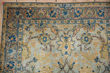 Close-up of distressed Tabriz rug with pale blue field, gold, indigo palmettes, and vinery.