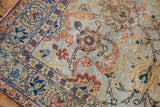 Distressed border and corner of vintage Tabriz rug with faded terracotta, indigo, and pale blue florals.