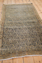 Patinaed navy floral and boteh patterns on distressed antique Malayer rug's beige field and border.