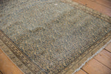 Distressed antique Malayer rug with low pile, navy floral motifs on beige, and fringe.