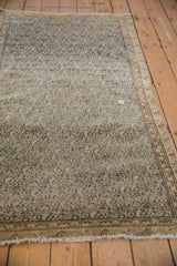 Antique Malayer rug with storied wear on beige pile, navy patterns, and visible fringe.
