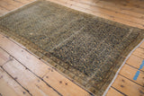 Distressed Malayer rug corner, showing worn navy Persian motif and visible foundation.