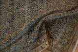 Distressed texture of an antique Malayer rug showing navy boteh pattern and visible foundation.