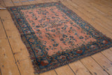 Antique Manchester Kashan rug close-up: dusty rose field, scrolling vinery, worn texture, and cobalt border.
