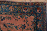 Antique Kashan rug corner: dusty rose field, scrolling vinery, cobalt blue floral border, subtle wear.