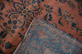 Antique Manchester Kashan rug folded, showing dusty rose floral pile, wear, and its blue woven foundation.
