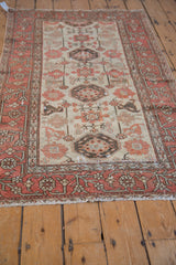 Distressed Hamadan rug corner: terracotta vine border and antique ivory geometric field.