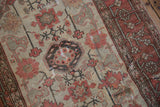 Distressed pile detail showing geometric floral arabesques and meandering vine border in terracotta and ivory.