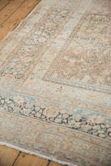 Distressed Meshed carpet corner featuring elaborate floral motifs in pale copper and dusty blue.