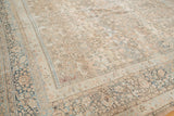 Faded floral motifs and abrashes in beige and pale blue on a distressed Persian Meshed carpet.