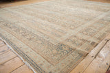 Fringed corner of a distressed Meshed carpet, showcasing pale copper and dusty blue floral borders.