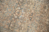 Distressed pile showing time-softened copper and dusty blue floral motifs on a vintage Meshed rug.
