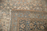 Distressed floral design in pale copper and blue on a vintage Meshed rug, showing its woven foundation.
