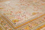 Antique Oushak rug corner detail, revealing low pile rectilinear floral patterns and colorful borders.