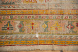 Worn lower edge of antique Oushak carpet, exposing foundation with saffron, red, and dusty teal patterns.