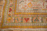 Antique Oushak corner detail with aged pile, rectilinear floral motifs in saffron, rose, and teal.