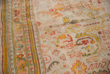 Antique Oushak carpet texture with worn knot heads, exposed foundation, and saffron, rose, teal motifs.
