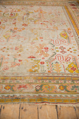 Worn fringe and rectilinear border of the antique Oushak carpet, showing saffron, rose, and teal.