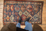 Antique Kuba rug left border, showing madder red serrated guls on indigo blue field with mostly even wear.