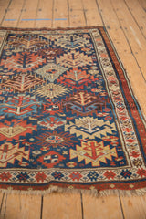 Bottom edge and fringe of antique Kuba rug, with geometric borders and stylized tree motifs in madder red, indigo blue, ivory.