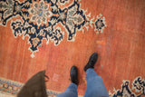 Abrashed terracotta field with navy and ivory floral motifs on a vintage Mahal carpet.