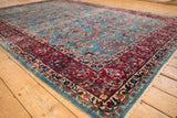 Deep wine red meandering vine border and sky blue millefleur field on a vintage Kerman carpet.