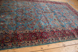 Vintage Kerman carpet's cochineal red floral border meeting worn sky blue millefleur field.