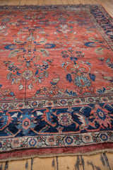 Distressed vintage Mahal carpet detail: brick red floral field meets navy Herati border with palmettes.