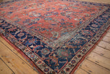 Distressed vintage Mahal carpet corner, navy blue Herati border, brick red field, foundation visible.