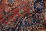 Distressed Mahal carpet's worn texture: brick red field, navy Herati border, low pile.